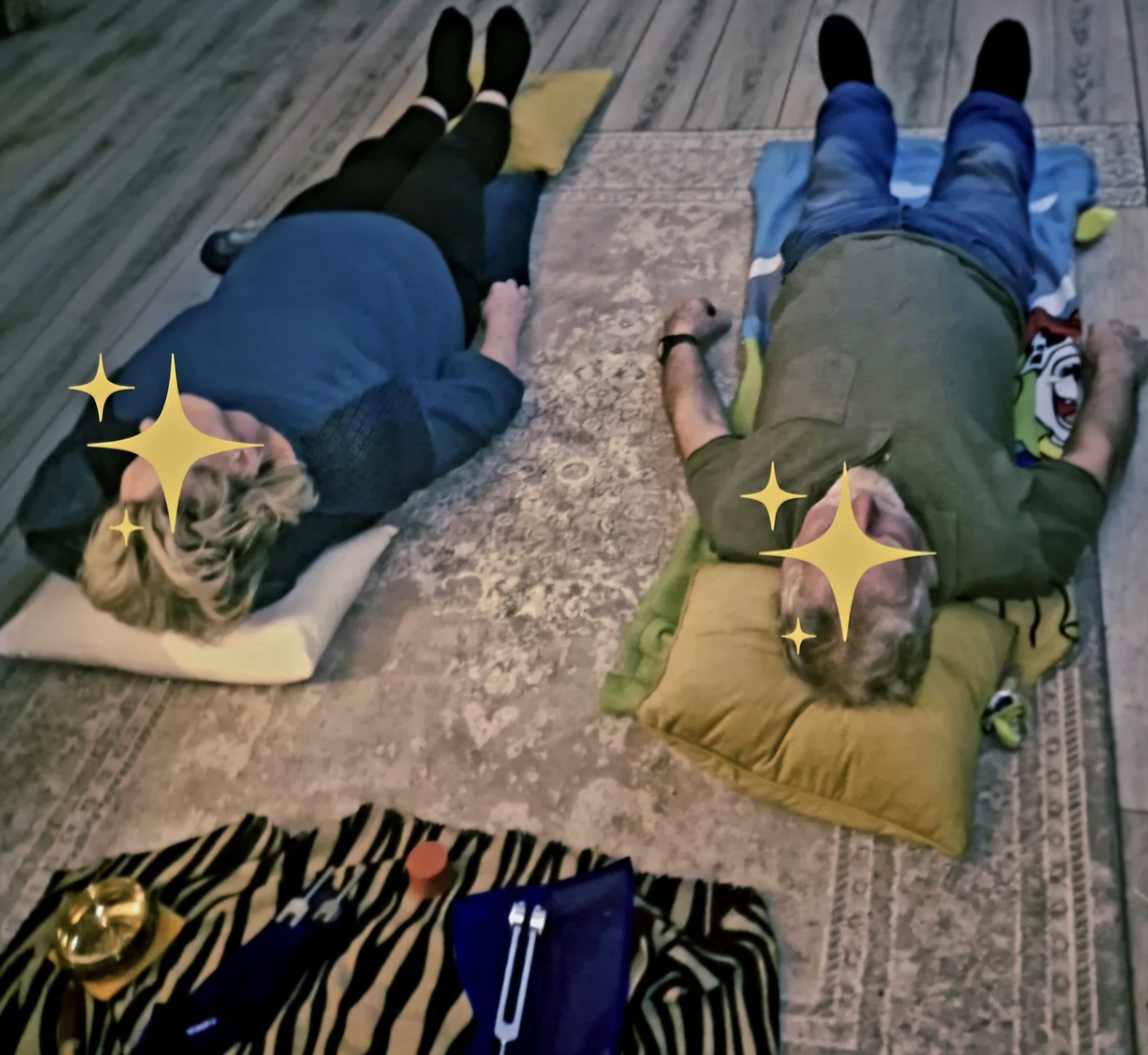 Two people resting during a sound healing session with tuning forks and a gong nearby